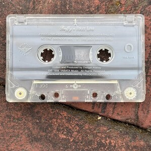 May include: A clear cassette tape labeled "Buffy - First Love." The tape includes song titles like "First Love" and "No One." The cassette is marked with "Velocity Records" and the year 1996.
