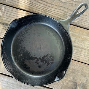 May include: A black cast iron skillet with a loop handle. The skillet has a worn, seasoned surface.
