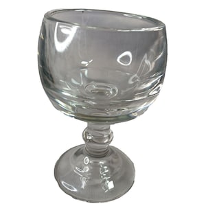 May include: A clear glass goblet featuring a rounded, bulbous bowl and a thick, multi-tiered stem that connects to a wide, circular base. The glass is transparent with smooth, reflective surfaces and a sturdy, balanced construction.
