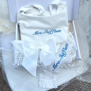 May include: A white tank top and white lace underwear set inside a white box. The tank top features the blue embroidered text Mrs. Shifflett. The lace underwear includes a large white satin bow and the blue embroidered text Mrs. Shifflett.