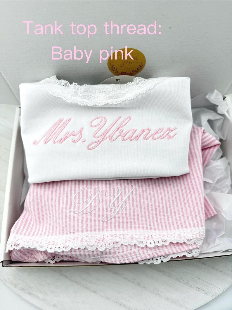 May include: A white tank top with lace trim and the embroidered text Mrs. Ybanez in baby pink thread, paired with a pink and white striped garment featuring white lace trim and the embroidered initials DY in white thread.