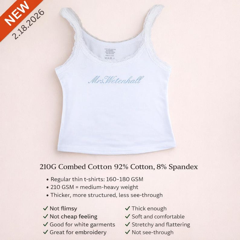 May include: A white sleeveless tank top with lace trim along the neckline and armholes. The chest features the blue embroidered text Mrs.Wetenhall. The garment is made of 210G combed cotton, 92% cotton, and 8% spandex fabric blend.