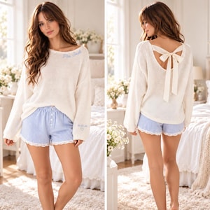 May include: A cream-colored long-sleeve knit sweater with blue embroidered text reading Mrs. Smith and 10.10.26 with a heart, paired with light blue and white pinstriped shorts featuring a white lace trim and a back ribbon tie closure.
