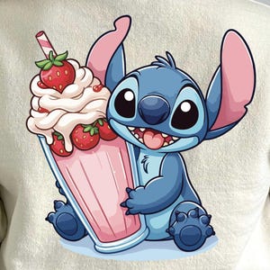 Pode incluir: Um personagem de desenho animado azul com olhos grandes e um milkshake rosa com morangos. O personagem está segurando o milkshake com uma mão.