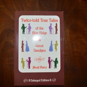 May include: A book cover with a red background and white text. The title is "Twice-told True Tales of the Blue Ridge & Great Smokies". The author is Mead Parce. The book is an enlarged edition.
