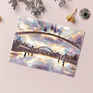 Può includere: Un dipinto ad acquerello di un ponte su un fiume con edifici su entrambi i lati. Il cielo è un mix di viola, blu e arancione.
