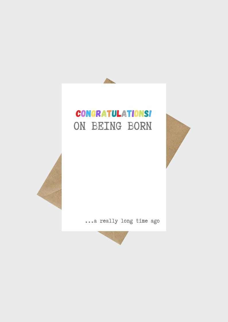 May include: A white card with the text "CONGRATULATIONS! ON BEING BORN... a really long time ago" in black and colorful letters.