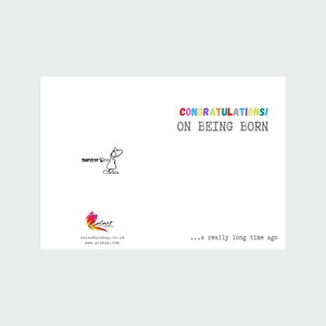 May include: A humorous greeting card with a cartoon stick figure pointing to the text "Congrats! On being born... a really long time ago". The card is white with a rainbow colored logo in the bottom left corner.