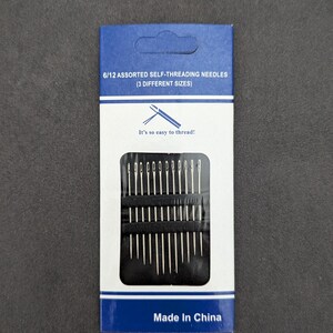 May include: A pack of 6/12 assorted self-threading needles in three different sizes. The needles are silver and are packaged in a clear plastic case with a black background. The pack is blue and white with the text "6/12 assorted self-threading needles (3 different sizes)" and "It's so easy to thread!" The pack also says "Made in China".