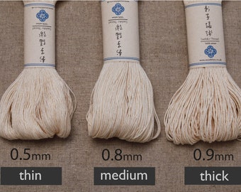 May include: Three skeins of off-white Sashiko thread with paper labels, labeled 0.5mm thin, 0.8mm medium, and 0.9mm thick. Each skein is made of 100% cotton and features Japanese characters and the text Sashiko Thread on the paper band.