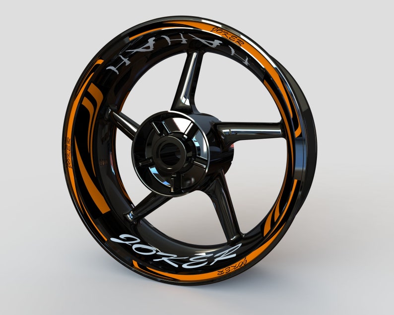 May include: Black motorcycle wheel rim with an orange and black graphic design that says "Joker" and "90ZR".