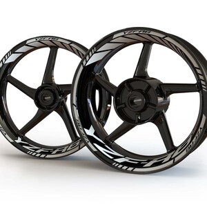 May include: Two black motorcycle wheels with silver YZF-R6 decals. The decals are on the outer rim of the wheels and have a white stripe running along the edge.