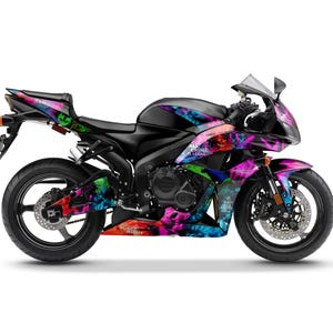 May include: A black sport motorcycle with a vibrant, colorful graphic design. The design incorporates shades of pink, purple, blue, and green. The text "ALL CRIME IS LEGAL" and "PURGE NIGHT" is visible on the motorcycle.