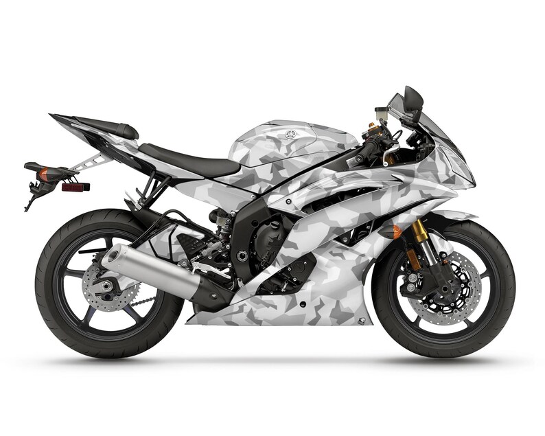 Pu&ograve; includere: Una motocicletta Yamaha con mimetica bianca e grigia. La moto sportiva ha ruote nere, un sedile nero e forcelle anteriori dorate. La motocicletta &egrave; su sfondo bianco.