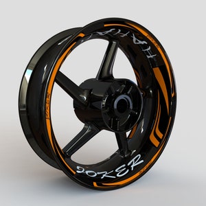 May include: Black motorcycle wheel rim with an orange and black graphic decal that says "Joker" and "414" in white lettering.