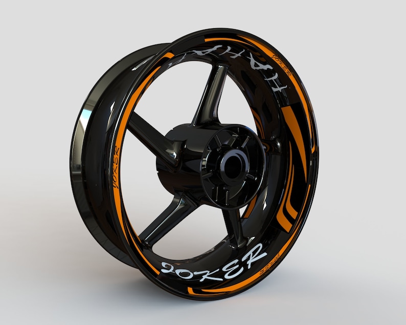 May include: Black motorcycle wheel rim with an orange and black graphic decal that says "Joker" and "414" in white lettering.
