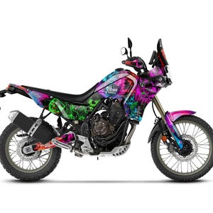 Può includere: Una moto colorata con un design vibrante nei toni del rosa, viola, verde e blu. Il testo "ALL CRIME IS LEGAL" è visibile sul lato. La moto ha pneumatici neri e uno scarico nero.