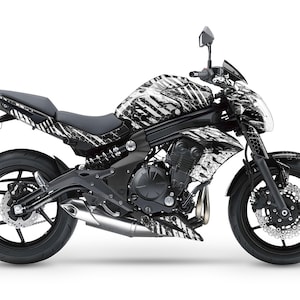 May include: A black and white motorcycle with a zebra-like pattern on the body and wheels. The motorcycle has a black seat and a black exhaust pipe.