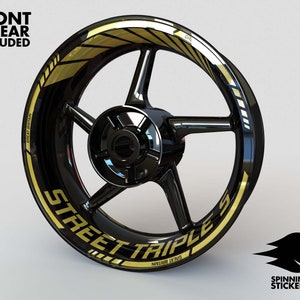 Puede incluir: Llantas de rueda de motocicleta negras con una franja dorada y el texto "STREET TRIPLE S" en letras doradas.