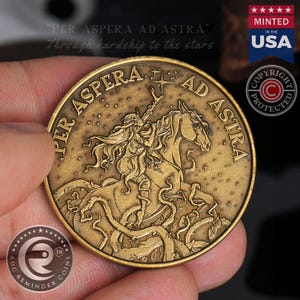 May include: A circular bronze-toned metal coin featuring a raised relief design of a figure riding a horse amidst tangled vines and a starry sky. The text PER ASPERA AD ASTRA is embossed along the upper edge of the coin, surrounding the central imagery.
