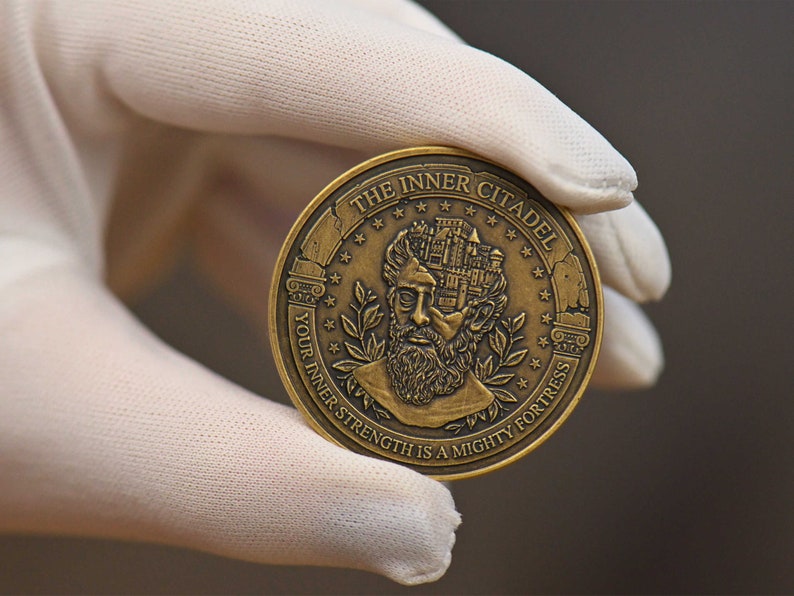 Op de afbeelding: Een ronde, bronskleurige metalen munt met een reli&euml;f van een bebaarde figuur met een kasteel in het hoofd verwerkt. De tekst THE INNER CITADEL en YOUR INNER STRENGTH IS A MIGHTY FORTRESS staat in reli&euml;f langs de cirkelvormige rand.