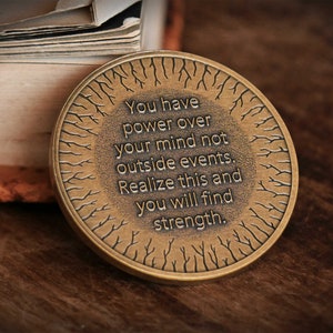 May include: A round, bronze-colored coin with a tree-like design and the inscription "You have power over your mind not outside events. Realize this and you will find strength."