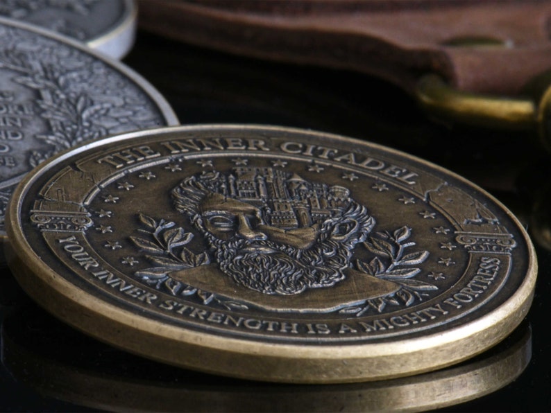 Op de afbeelding: Een ronde, bronskleurige metalen munt met een reli&euml;f van een bebaard figuur met een kasteel in het hoofd verwerkt. De tekst luidt THE INNER CITADEL en YOUR INNER STRENGTH IS A MIGHTY FORTRESS, omringd door kleine sterren en laurierbladeren.