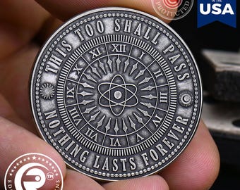 May include: A circular silver-toned metal coin featuring an atom symbol at the center, surrounded by Roman numerals from I to XII. The text THIS TOO SHALL PASS and NOTHING LASTS FOREVER is embossed along the outer edge with a sun and moon icon.