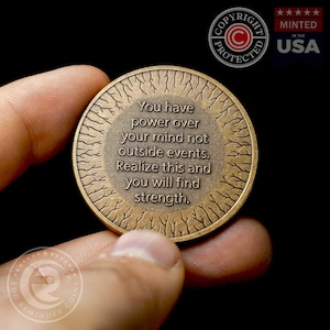 May include: A bronze-colored coin with a tree-like design around the edge. The coin has the text "You have power over your mind not outside events. Realize this and you will find strength."