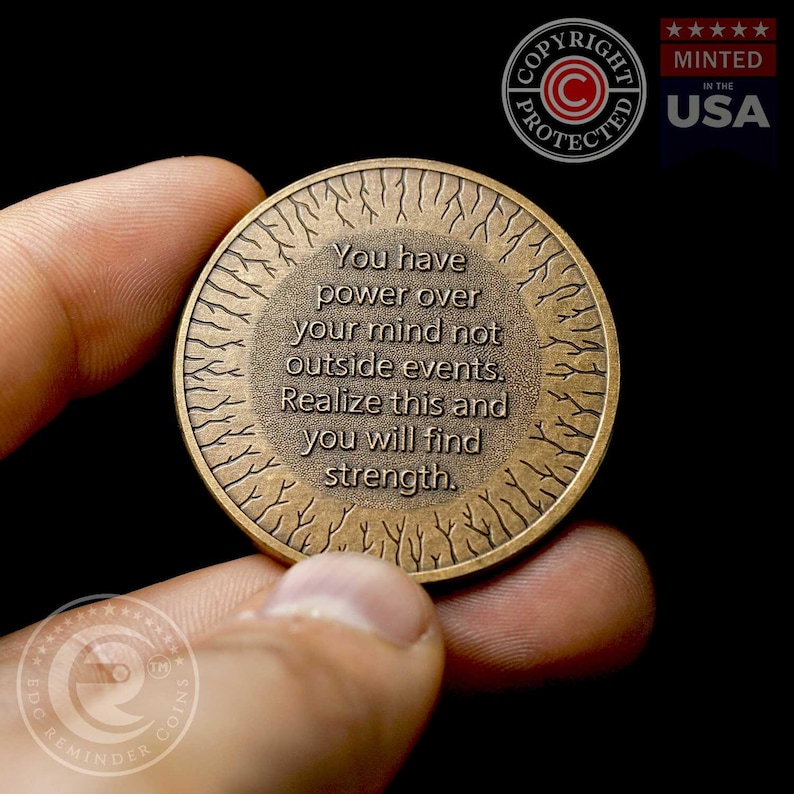 May include: A bronze-colored coin with a tree-like design around the edge. The coin has the text "You have power over your mind not outside events. Realize this and you will find strength."