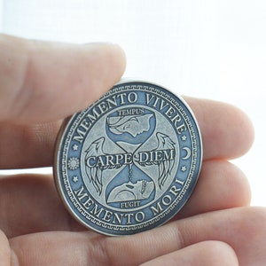 May include: Silver-toned round coin with an hourglass design and the text "Memento Vivere", "Carpe Diem", "Memento Mori", and "Tempus Fugit".