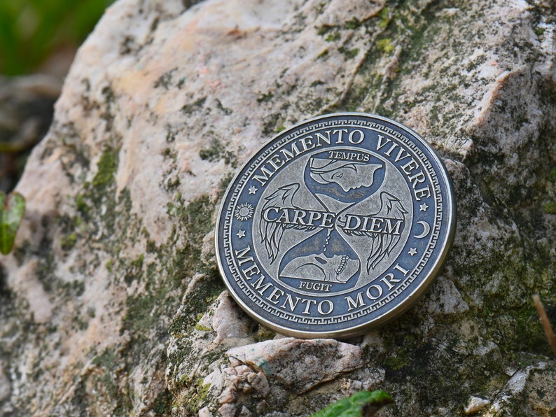 May include: A silver-toned round coin with an hourglass design and the Latin phrases "Memento Vivere", "Carpe Diem", and "Memento Mori" inscribed around the edge.