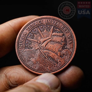 Könnte beinhalten: Eine kupferfarbene Münze mit einem detaillierten Bild eines Schiffes, das durch stürmische See fährt. Die Münze trägt die lateinische Phrase "Nulla Tenaci Invia Est Via" am Rand.