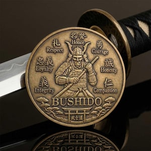 May include: A bronze-colored coin featuring a samurai warrior with the word "BUSHIDO" and Japanese characters. The coin is inscribed with words like "Respect," "Loyalty," and "Integrity." A katana sword and its hilt are visible in the background.