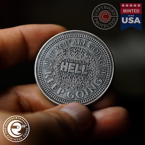 May include: A silver-toned coin with the text "If you are going through hell keep going" around the edge. The center of the coin features a stylized image of flames with the word "HELL" in the center.