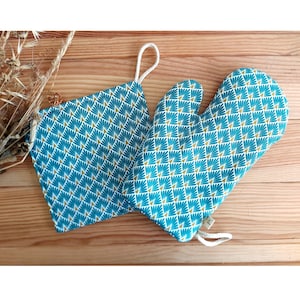 May include: A set of teal and gold oven mitts with a geometric pattern. The mitts are made of fabric and have a loop for hanging.