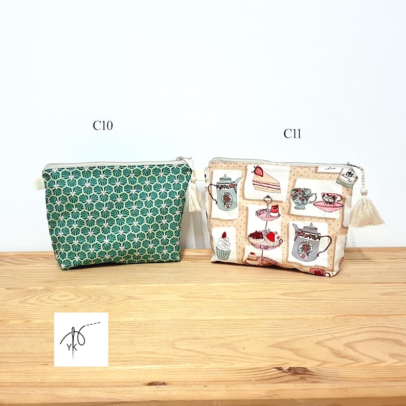 May include: Two rectangular zippered pouches with tassels. The left pouch, labeled C10, features a green and white geometric fan pattern. The right pouch, labeled C11, has a beige background with a print of teapots, teacups, and desserts.