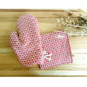 Peut inclure: Une paire de maniques de cuisine à motifs rouge et blanc. Les maniques sont en tissu et ont un motif géométrique.