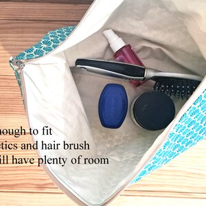 May include: A teal and white patterned zippered pouch with a white lining. The pouch is open and contains a hairbrush, a bottle of pink liquid, a blue container, and a black container.
