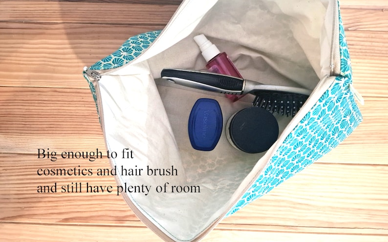 May include: A teal and white patterned zippered pouch with a white lining. The pouch is open and contains a hairbrush, a bottle of pink liquid, a blue container, and a black container.