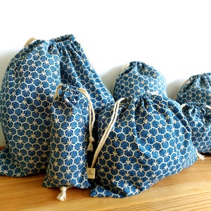 Pode incluir: Conjunto de cinco sacos de cord&atilde;o azul e branco com um padr&atilde;o geom&eacute;trico. Os sacos s&atilde;o feitos de tecido e t&ecirc;m um cord&atilde;o de algod&atilde;o natural.