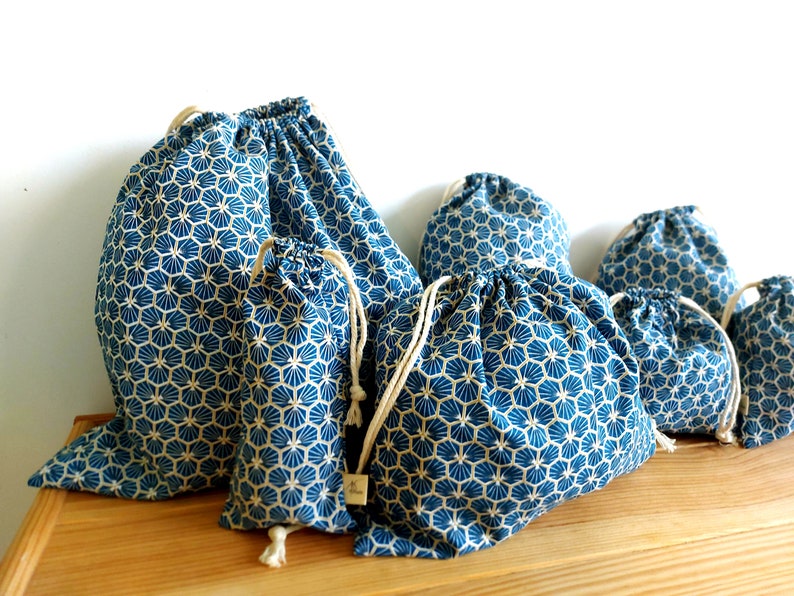 Pode incluir: Conjunto de cinco sacos de cord&atilde;o azul e branco com um padr&atilde;o geom&eacute;trico. Os sacos s&atilde;o feitos de tecido e t&ecirc;m um cord&atilde;o de algod&atilde;o natural.