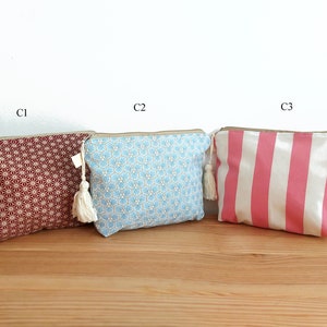 May include: Three rectangular zippered pouches with tassels. C1 is dark red with a white geometric star pattern. C2 is light blue with a white and gold hexagonal floral print. C3 features vertical pink and white stripes. Each has a beige zipper.