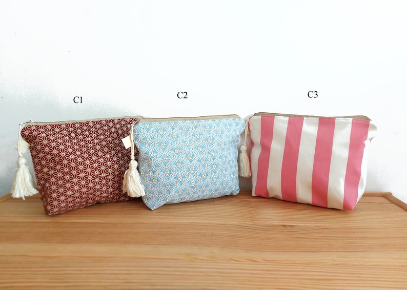 May include: Three rectangular zippered pouches with tassels. C1 is dark red with a white geometric star pattern. C2 is light blue with a white and gold hexagonal floral print. C3 features vertical pink and white stripes. Each has a beige zipper.