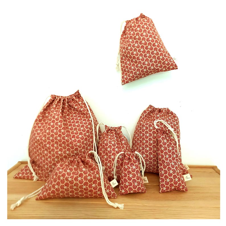 May include: Set of six red and white drawstring bags with a geometric pattern. The bags are made of fabric and come in a variety of sizes.