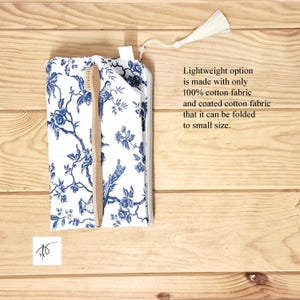 May include: A white fabric pouch with a blue floral and bird pattern, featuring a zipper closure with a white tassel. A light brown wooden toothbrush is placed on top of the pouch. The text reads: Lightweight option is made with only 100% cotton fabric and coated cotton fabric that it can be folded to small size.