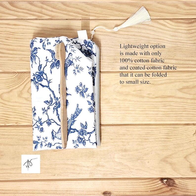 May include: A white fabric pouch with a blue floral and bird pattern, featuring a zipper closure with a white tassel. A light brown wooden toothbrush is placed on top of the pouch. The text reads: Lightweight option is made with only 100% cotton fabric and coated cotton fabric that it can be folded to small size.
