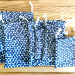 Pode incluir: Conjunto de seis sacos de cord&atilde;o azul e branco com um padr&atilde;o geom&eacute;trico. Os sacos s&atilde;o feitos de tecido e t&ecirc;m um fecho de cord&atilde;o branco.