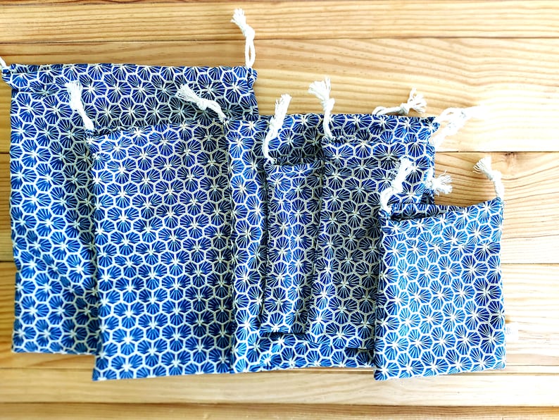 Pode incluir: Conjunto de seis sacos de cord&atilde;o azul e branco com um padr&atilde;o geom&eacute;trico. Os sacos s&atilde;o feitos de tecido e t&ecirc;m um fecho de cord&atilde;o branco.
