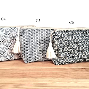 May include: Three zippered pouches labeled C4, C5, and C6. The first features a grey and white fan pattern, the second a black and white geometric star print, and the third a black and white honeycomb design. Each pouch includes a cream tassel.